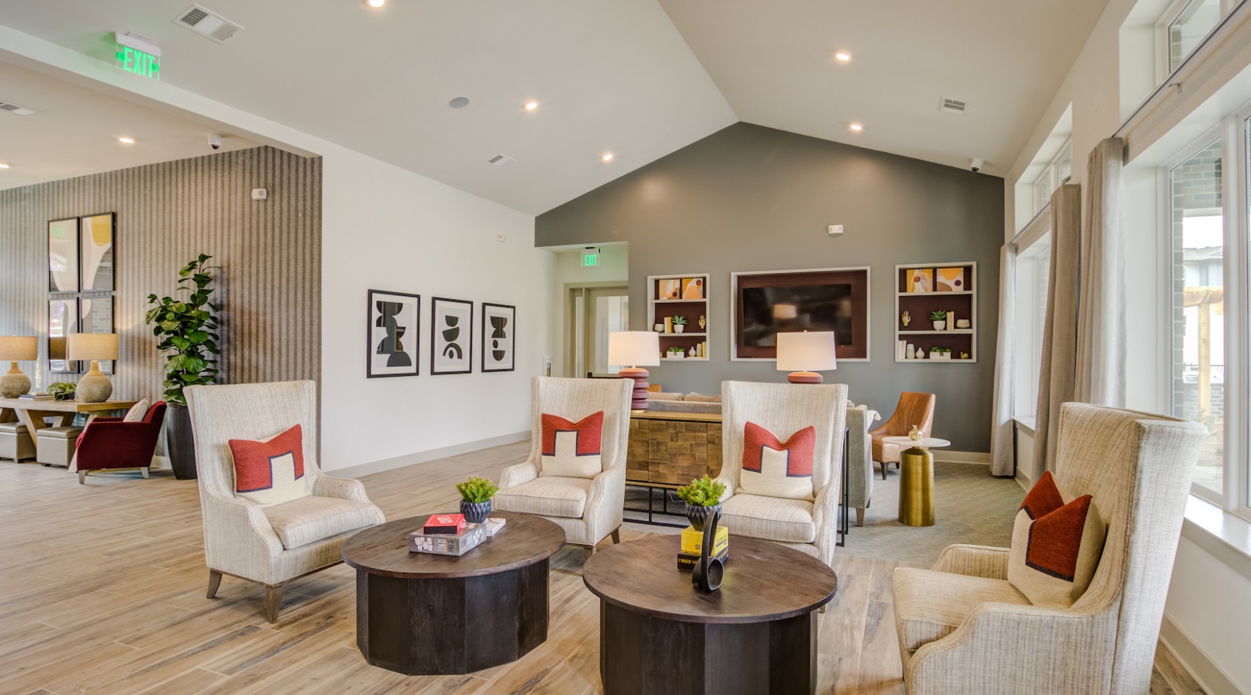 Clubroom Common lounge at our apartments in Jefferson, featuring wood grain floor paneling, a flat screen TV, and cushioned chairs.