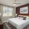 Model bedroom at our apartments in Jefferson, featuring a maroon wall, white bedspread, and a large window. 